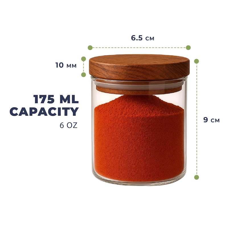 May include: A clear glass jar filled with bright orange powder, topped with a wooden lid. The jar has a 175 ml or 6 oz capacity. Dimensions shown are 6.5 cm in diameter, 9 cm in height, and a 10 mm lid thickness.