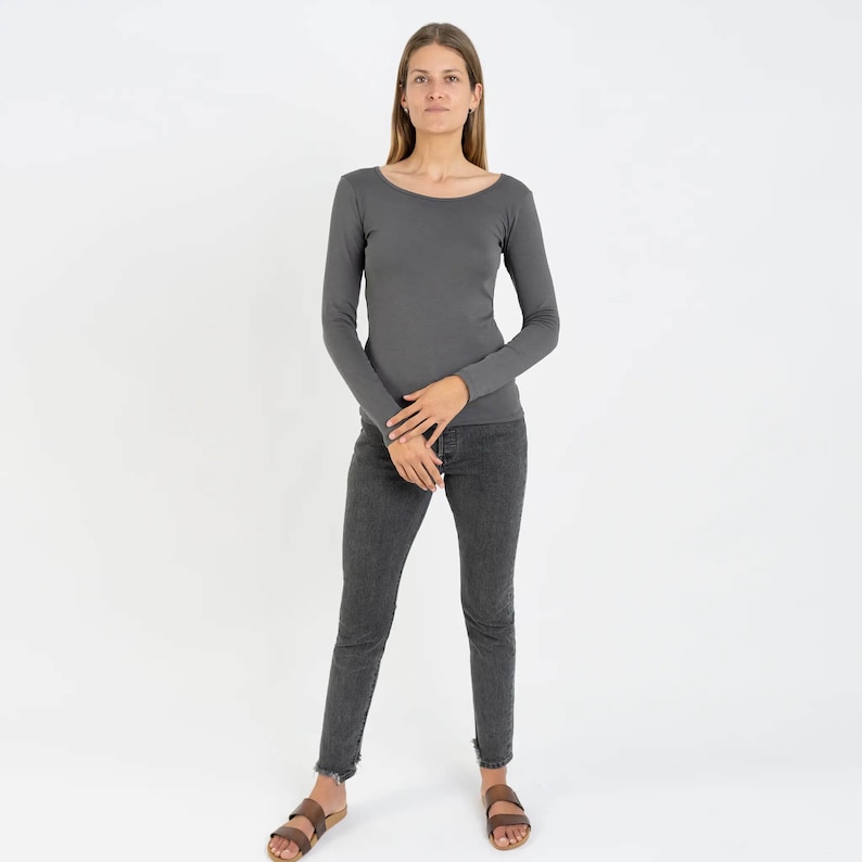 May include: A charcoal gray long-sleeved shirt with a scoop neck. The shirt is fitted and has a casual look.