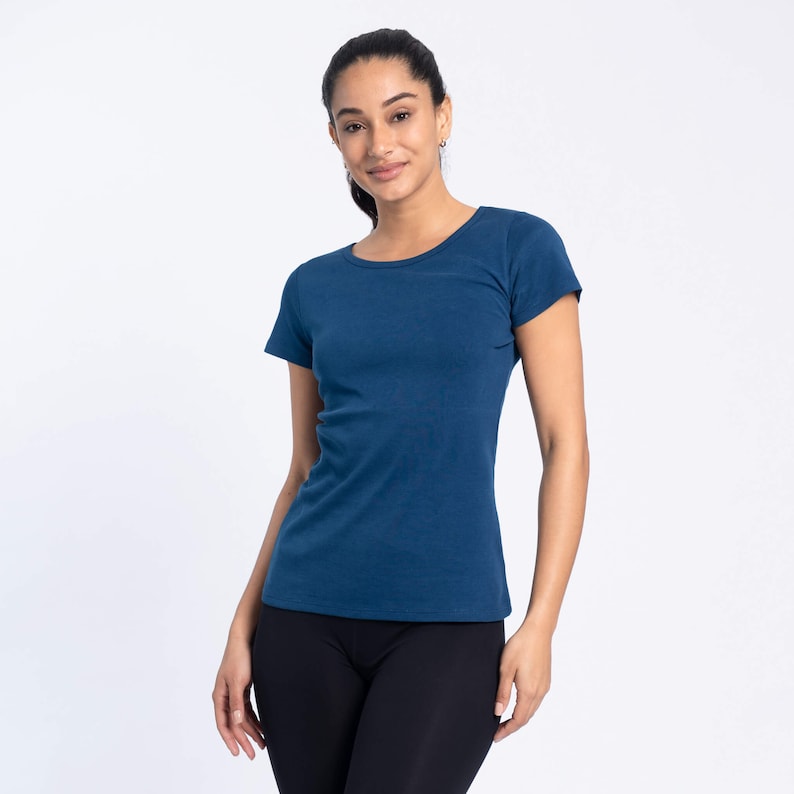 May include: A woman wearing a dark blue short-sleeved t-shirt and black trousers.