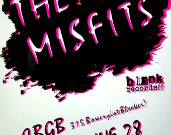 May include: A white poster with the words "THE MISFITS" in white letters with a pink outline, set against a black cloud-like shape. Below, it reads "CBGB Tuesday JUNE 28". The poster also includes "blank records!!".