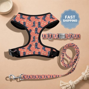 May include: A dog harness, collar, and leash set with a repeating pattern of navy blue cowboy boots and small yellow flowers on a coral background. The harness and collar have black trim. The leash has a silver-colored clasp.