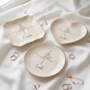 May include: A set of three ceramic mugs with a speckled, matte finish. The mugs are in shades of cream, light gray, and dark gray. Each mug has a simple, minimalist design and a rounded handle.