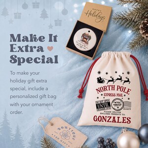 May include: A round white ceramic ornament inside a brown cardboard box labeled Happy Holidays, and a cream-colored drawstring gift bag with red cords. The bag features black and red text reading North Pole Express Mail and Gonzales.