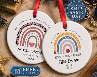 May include: Two round white ceramic ornaments with red ribbon hangers. The left ornament features a leopard print rainbow, a pink heart, and text reading To Teach is To Touch a Life For, Mrs. Webb, 3rd Grade, 2026. The right ornament shows a pencil rainbow, a red apple, and text reading It takes a big heart to shape little minds, TEACH LOVE INSPIRE, Mrs. Laura, PRE-K, 2026.