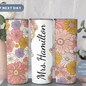 May include: Three stainless steel tumblers with a floral design. The center tumbler has the text "Mrs. Hamilton" on it. The tumblers come with a straw.