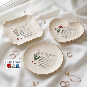 May include: Three cream-colored ceramic trinket dishes with gold-trimmed edges. One square, one heart-shaped, and one round dish feature floral illustrations, butterflies, and the text Chapter Sixty, Happy 60th Birthday, and individual names.