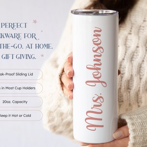 May include: White stainless steel tumbler with a pink inscription that reads "Mrs. Johnson". The tumbler has a sliding lid and is 20 fluid ounces in capacity.