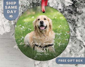 May include: A round, white, glass bauble with a photo of a golden retriever dog in a grassy field. The bauble has the text "in loving memory of LUCKY 2010 - 2024" written on it.