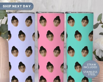 May include: Three stainless steel tumblers in pastel colors: lavender, pink, and teal. Each tumbler is covered in a repeating pattern of a woman's face. The tumblers have a silver rim and come with a straw. The text "STRAW INCLUDED" and "STAINLESS STEEL" is visible.