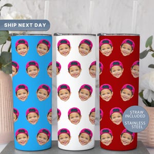 May include: Three stainless steel tumblers with a repeating pattern of a child's face wearing a pink cap. One tumbler is blue, one is white, and one is red. The tumblers include a straw and are labeled "Straw Included" and "Stainless Steel."
