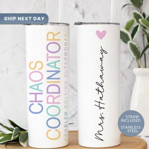 May include: Two white stainless steel tumblers with lids and straws. The tumbler on the left has the text "Chaos Coordinator Problem Solving Superwoman" in rainbow colors. The tumbler on the right has the text "Mrs. Hathaway" in black cursive with a pink heart above the text.