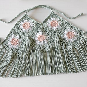 K&ouml;nnte beinhalten: Ein geh&auml;keltes Halstuch mit gr&uuml;ner Basis und wei&szlig;en und rosa G&auml;nsebl&uuml;mchen-Motiven. Das Tuch hat einen Fransenbesatz.