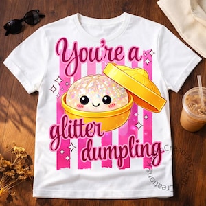 Puede incluir: Camiseta blanca con un gráfico de una bola de masa hervida con purpurina en un recipiente amarillo, con el texto "You're a glitter dumpling" en escritura rosa. El diseño incluye rayas verticales rosas y estrellas.