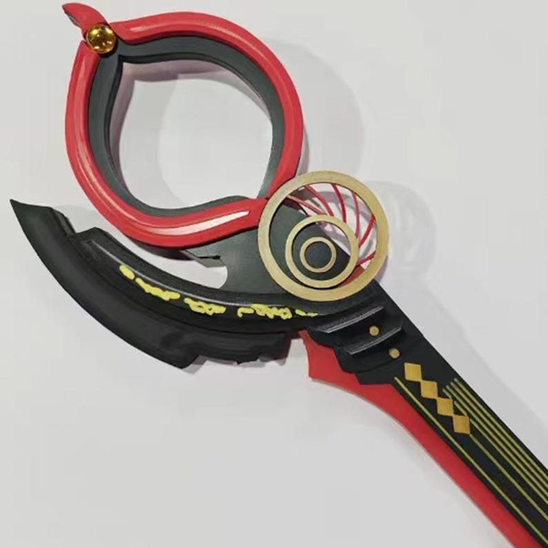 May include: A decorative, stylized weapon with a red and black color scheme. The design features a circular handle, a curved blade, and gold accents. The handle has a red outer ring and a black inner ring. The blade is black with gold detailing.