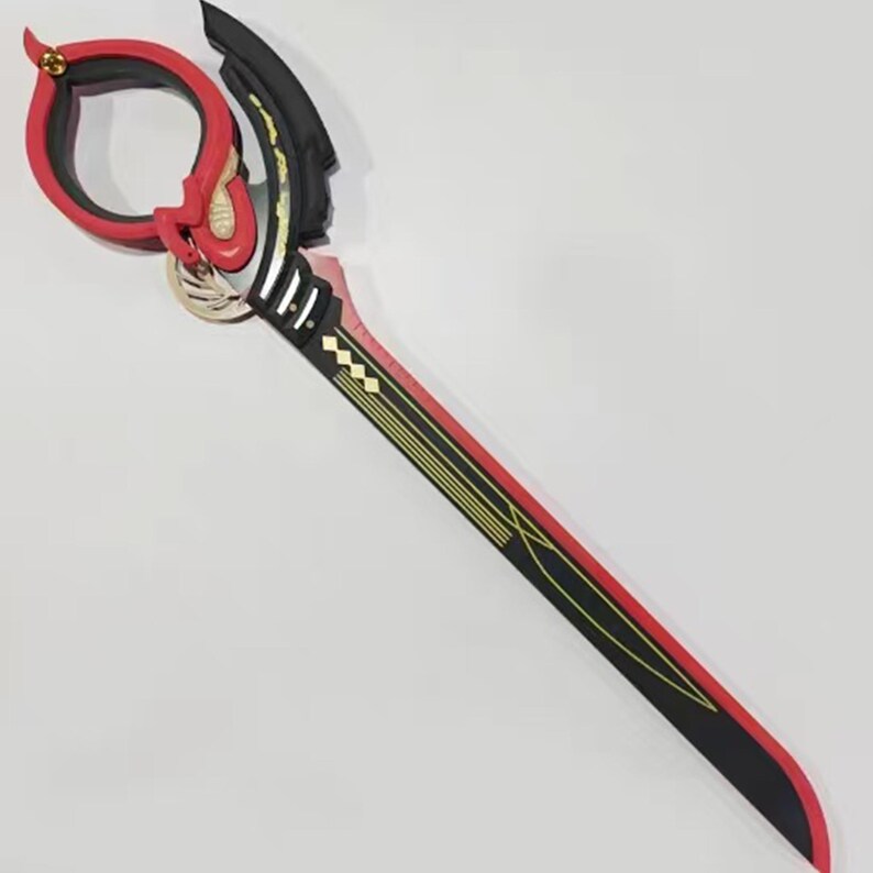 May include: A decorative sword with a red and black blade, featuring gold accents and a circular red handle. The handle has a gold clasp and a black grip. The sword is designed with a unique, stylized appearance.