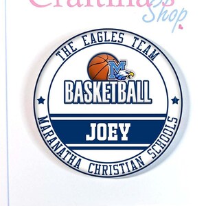 May include: A white card with a blue and white basketball themed circle sticker. The sticker says "The Eagles Team Basketball" with a basketball graphic and the text "Maranatha Christian Schools" around the edge. The sticker also has the name "Joey" in a blue banner.