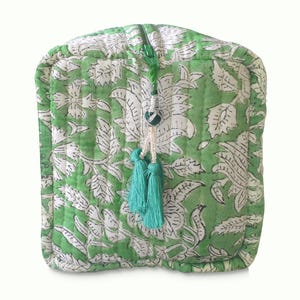 Front view of quilted toiletry bags hand block printed with a delicate green & white floral motif. Made of soft organic cotton with internal pockets for small items and a waterproof lining. Uses: Organize toiletries at home or as a travel bag 
Hand block printed by master Artisans in Jaipur, India. The subtle micro variations inherent to hand block printing create a look that cannot be recreated by any other method and ensure that each bag is essentially unique. 

Available in 3 sizes.