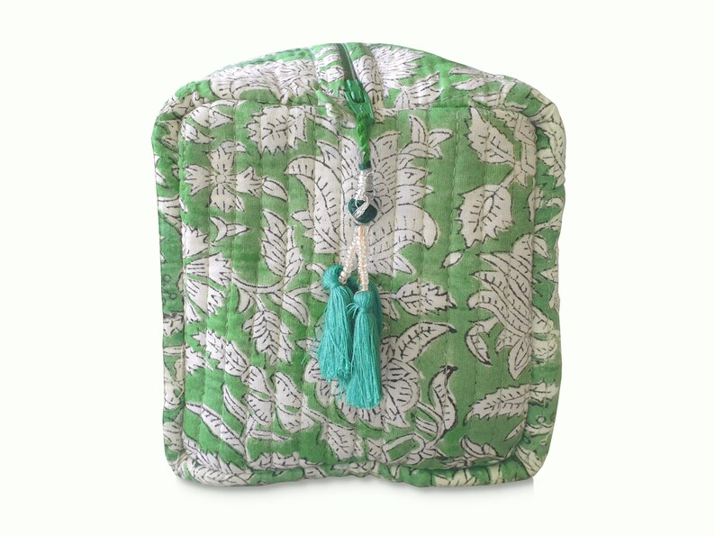 Front view of quilted toiletry bags hand block printed with a delicate green & white floral motif. Made of soft organic cotton with internal pockets for small items and a waterproof lining. Uses: Organize toiletries at home or as a travel bag 
Hand block printed by master Artisans in Jaipur, India. The subtle micro variations inherent to hand block printing create a look that cannot be recreated by any other method and ensure that each bag is essentially unique. 

Available in 3 sizes.