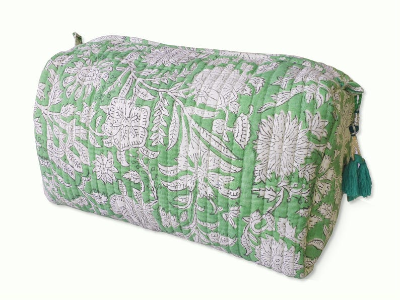 Side view of cute quilted toiletry bags hand block printed with a delicate green & white floral motif. Made of soft organic cotton with internal pockets for small items and a waterproof lining. Uses: Organize toiletries at home or as a travel bag 
Hand block printed by master Artisans in Jaipur, India. The subtle micro variations inherent to hand block printing create a look that cannot be recreated by any other method and ensure that each bag is essentially unique. 

Available in 3 sizes.