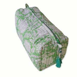 Top view of quilted toiletry bags hand block printed with a delicate green & white floral motif. Made of soft organic cotton with internal pockets for small items and a waterproof lining. Uses: Organize toiletries at home or as a travel bag 
Hand block printed by master Artisans in Jaipur, India. The subtle micro variations inherent to hand block printing create a look that cannot be recreated by any other method and ensure that each bag is essentially unique. 

Available in 3 sizes.