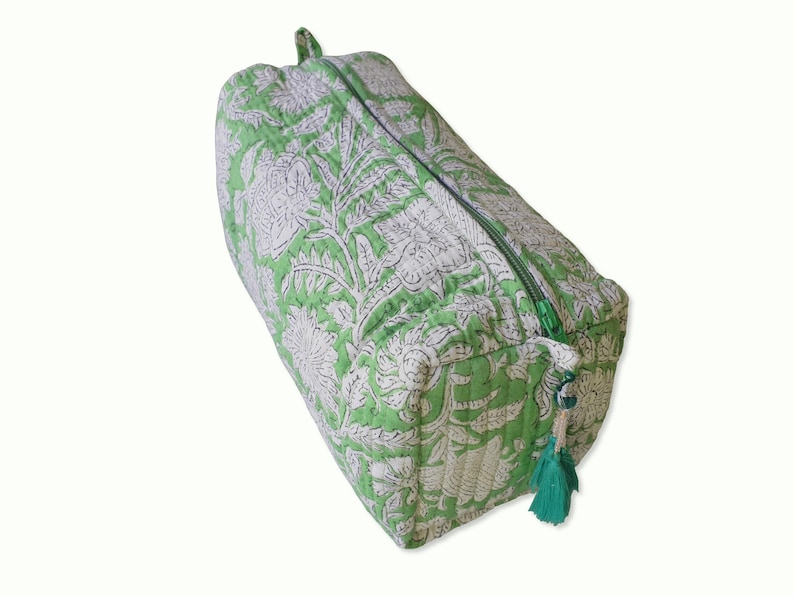Top view of quilted toiletry bags hand block printed with a delicate green & white floral motif. Made of soft organic cotton with internal pockets for small items and a waterproof lining. Uses: Organize toiletries at home or as a travel bag 
Hand block printed by master Artisans in Jaipur, India. The subtle micro variations inherent to hand block printing create a look that cannot be recreated by any other method and ensure that each bag is essentially unique. 

Available in 3 sizes.