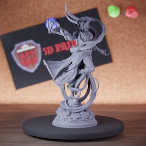 May include: A gray 3D-printed figurine of a fantasy character holding a glowing orb. The figure is on a round base, with a flowing cape and intricate details. A business card with the text "3D PRINT" is in the background.