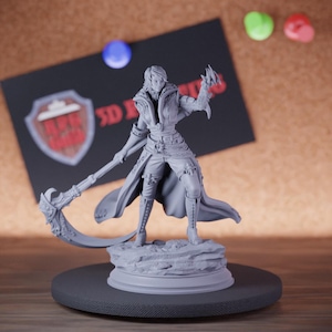 May include: A gray 3D-printed figurine of a character in a fantasy outfit, holding a scythe-like weapon. The figure stands on a rocky base atop a circular platform. A black sign with a logo and colorful push pins are in the background.