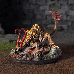 May include: A detailed miniature creature figurine with a textured, segmented body in shades of brown and yellow. It has red, tentacle-like appendages and a tail with red accents. The figurine is set on a rocky base.