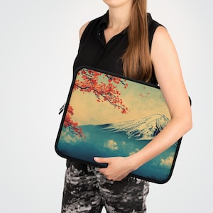 Könnte beinhalten: Eine schwarze Laptoptasche mit einem farbenfrohen Design, das eine Bergkette und einen Kirschblütenzweig zeigt. Das Design hat eine Vintage-Ästhetik mit einem verblassten Hintergrund.