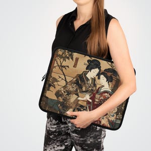 May include: A black laptop sleeve with a zipper closure features a vintage Japanese print of two women in traditional clothing. The print is in shades of brown, red, and gold.