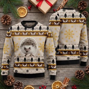 May include: A beige long-sleeve sweater featuring a central hedgehog graphic, surrounded by repeating patterns of deer, pine trees, and snowflakes in brown, black, and gold. The sweater has a black crew neckline, cuffs, and hem.