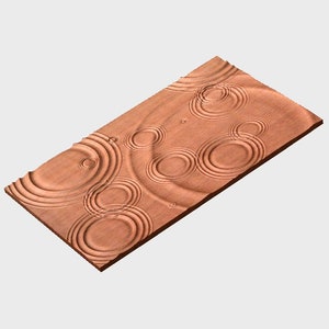 May include: A wooden wall panel featuring a raised design of concentric circles, reminiscent of water ripples. The panel is a light brown colour.