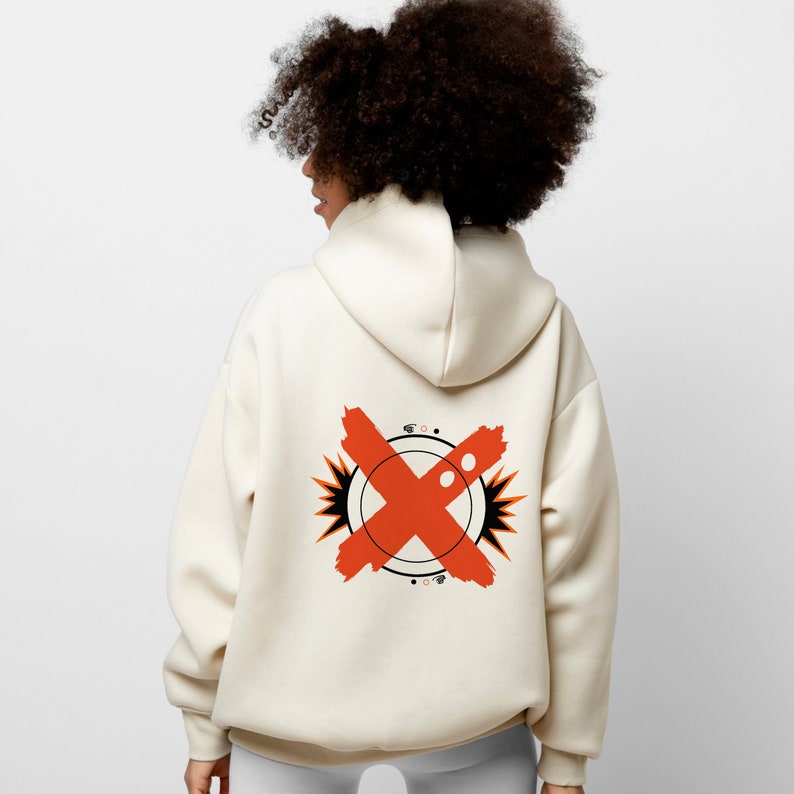 May include: A cream-colored hoodie with a red X graphic on the back. The graphic is surrounded by a black circle with white dots and orange starbursts.