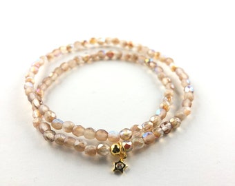 Könnte beinhalten: Ein doppelreihiges Armband aus irisierenden braunen Glasperlen mit einem goldenen Sternanhänger.