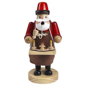Puede incluir: Una figura de madera de Papá Noel sosteniendo una bandeja con dos velas y un pequeño muñeco de nieve. Lleva un gorro rojo, una chaqueta roja y un delantal marrón. La figura está sobre una base de madera.