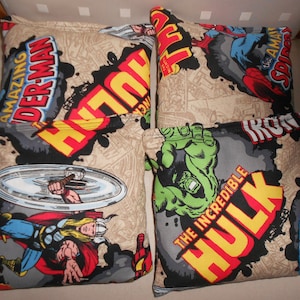 May include: Four fabric bean bags with different superhero designs. The bean bags are beige with black, red, yellow, and green comic book style graphics. The superheroes featured are The Incredible Hulk, Iron Man, Thor, and Spider-Man.