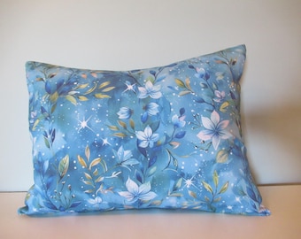 May include: A blue throw pillow with a floral pattern featuring white flowers and green leaves on a blue background with white speckles.