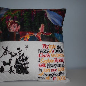 May include: A white pillow with a quilted pattern and embroidered images of Peter Pan, Captain Hook, and a pirate ship. The pillow has a flap that folds down to reveal a colorful image of Peter Pan and Tinkerbell flying through the air.