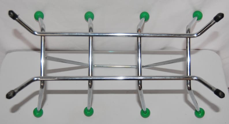 Peut inclure: Un rack en m&eacute;tal chrom&eacute; avec six pieds en plastique vert. Le rack a une forme rectangulaire avec une barre horizontale en haut et deux barres horizontales en bas.