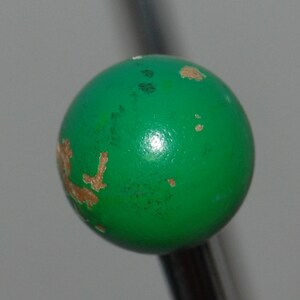 Peut inclure: Une boule verte avec des &eacute;clats de peinture brune et une surface brillante.
