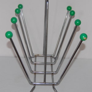 Peut inclure: Un porte-revues en chrome avec une base rectangulaire et six extr&eacute;mit&eacute;s en forme de boule verte sur les bras.