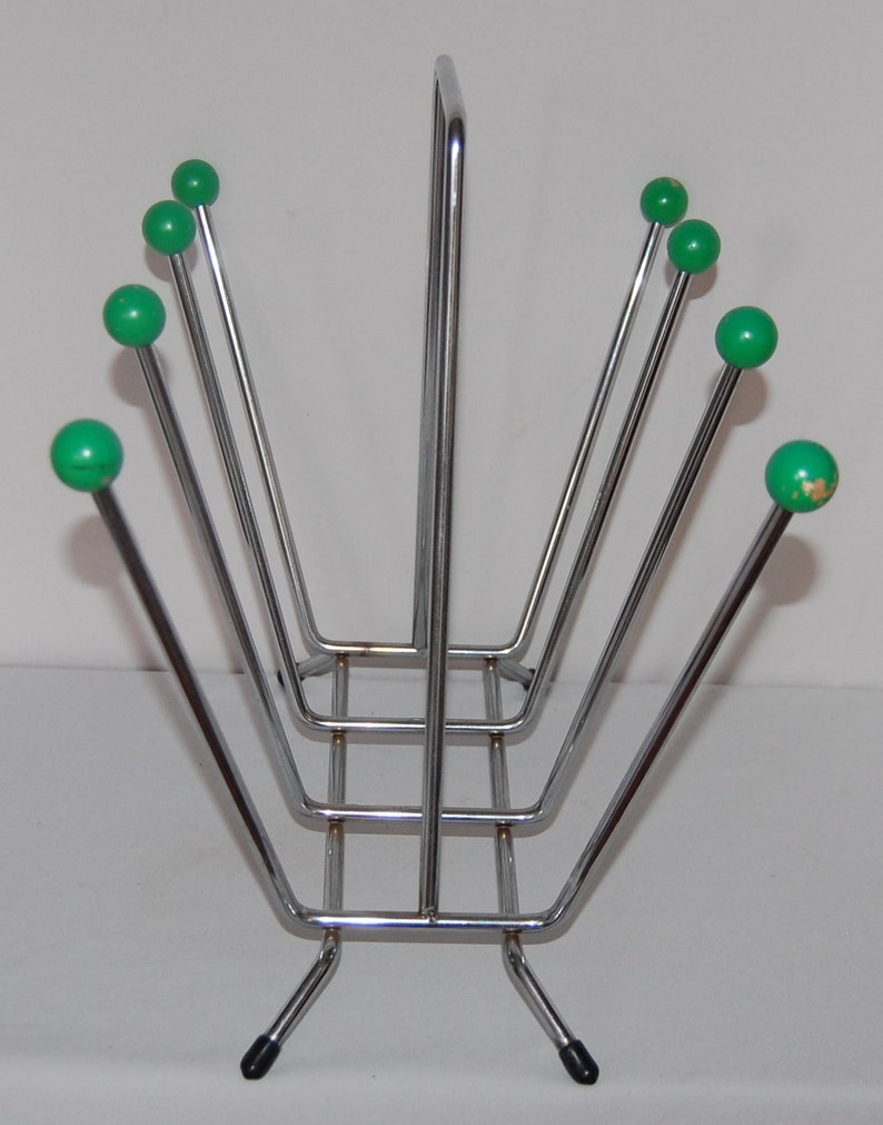 Peut inclure: Un porte-revues en chrome avec une base rectangulaire et six extr&eacute;mit&eacute;s en forme de boule verte sur les bras.
