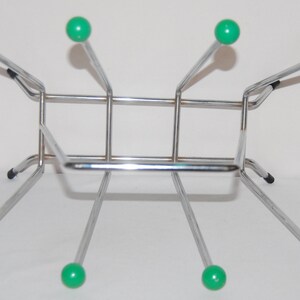 Peut inclure: Un porte-bouteilles en chrome avec six supports en plastique vert. Le porte-bouteilles a une base rectangulaire et quatre pieds.