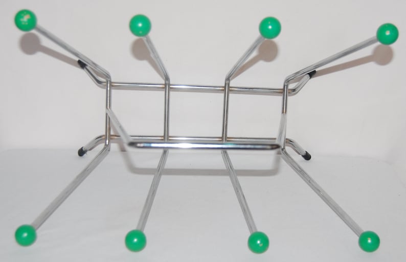 Peut inclure: Un porte-bouteilles en chrome avec six supports en plastique vert. Le porte-bouteilles a une base rectangulaire et quatre pieds.