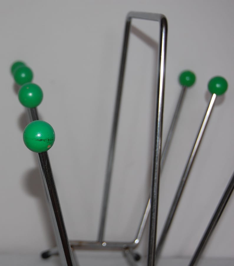 Peut inclure: Un porte-revues en chrome avec cinq extr&eacute;mit&eacute;s de boule vertes. Le porte-revues est fait de fines tiges m&eacute;talliques et a une base rectangulaire.