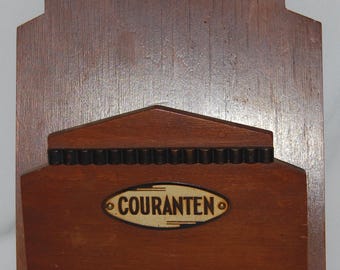 Peut inclure: Une boîte aux lettres murale en bois avec une garniture en métal noir et une étiquette dorée qui indique "COURANTEN".
