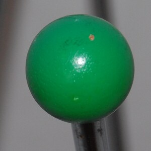 Peut inclure: Une boule verte sur une tige en m&eacute;tal argent&eacute;. La boule a une petite tache brune.