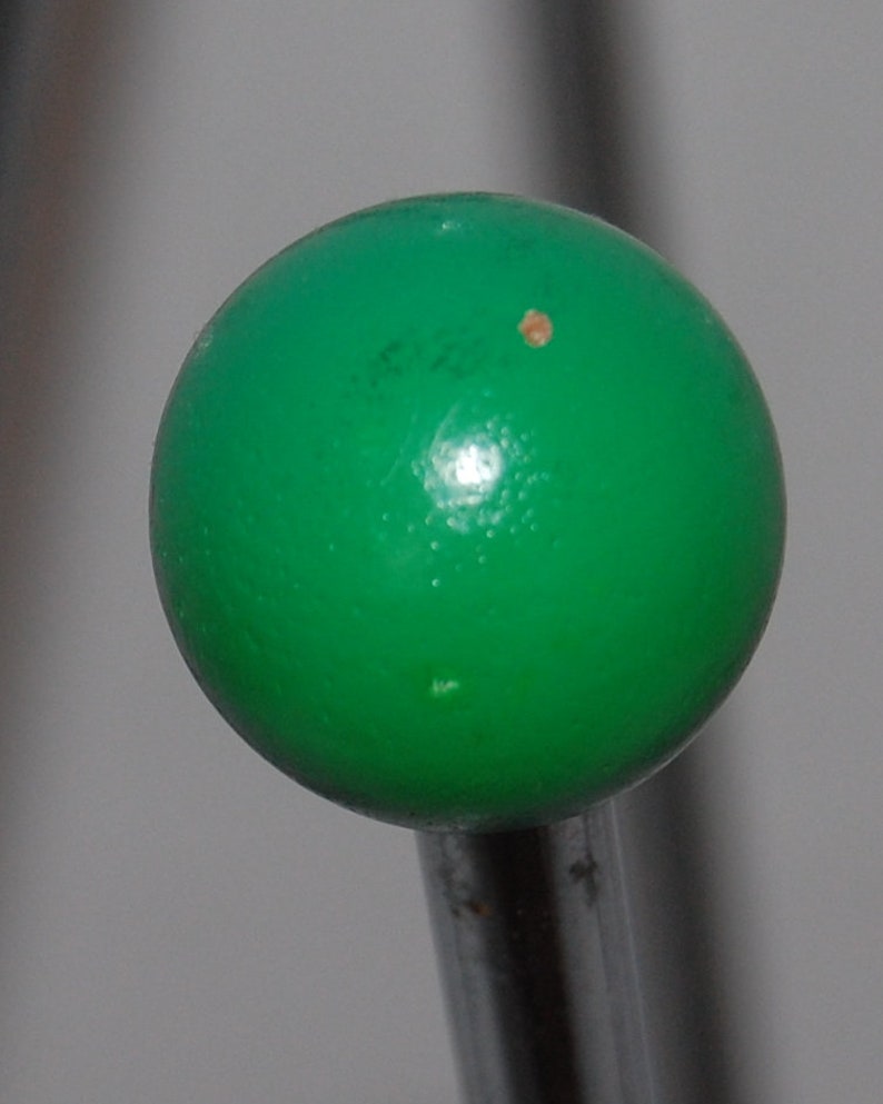 Peut inclure: Une boule verte sur une tige en m&eacute;tal argent&eacute;. La boule a une petite tache brune.