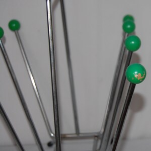 Peut inclure: Un porte-revues en chrome avec six extr&eacute;mit&eacute;s en forme de boule verte. Le porte-revues est en m&eacute;tal fin et a une base rectangulaire.