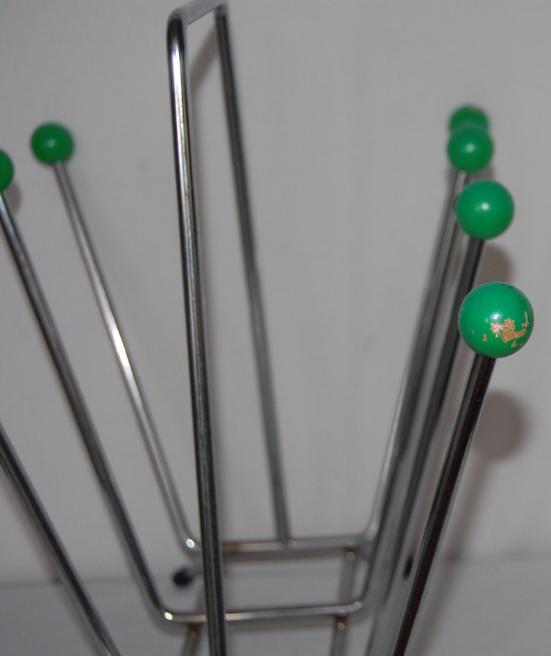 Peut inclure: Un porte-revues en chrome avec six extr&eacute;mit&eacute;s en forme de boule verte. Le porte-revues est en m&eacute;tal fin et a une base rectangulaire.